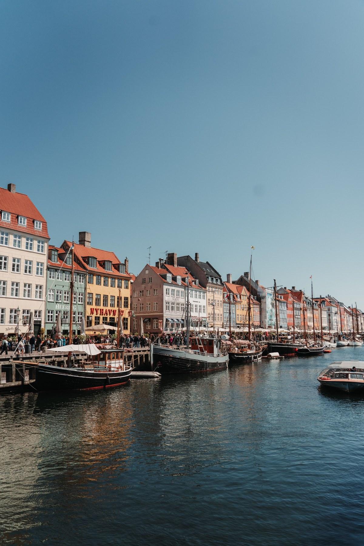 Colorful gabled houses lining a Copenhagen canal, wooden boats moored along the quay